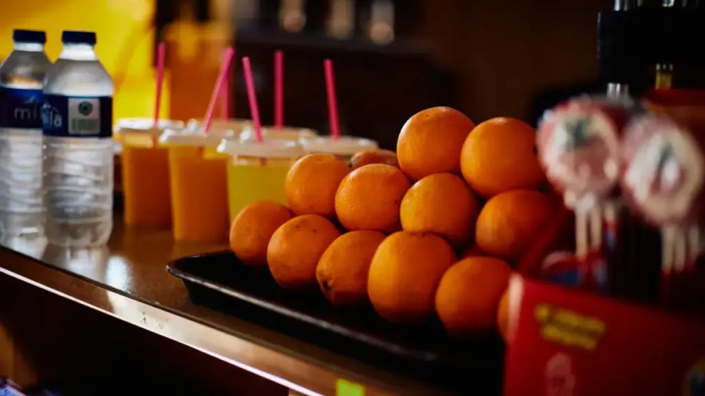 Ilustrasi tumpukan buah jeruk, jus buah, dan botol mineral terpajang di atas meja (Pexels)