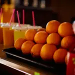 Ilustrasi tumpukan buah jeruk, jus buah, dan botol mineral terpajang di atas meja (Pexels)