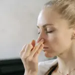seorang perempuan sedang menutup hidung