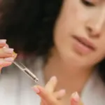 Potret seseorang menuangkan serum dalam pipet ke ujung telunjuk