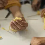 potret seseorang memegang pola crochet berwarna kuning.