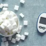 Potret bongkahan gula dalam mangkuk dan glukometer