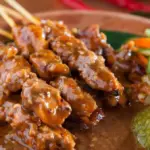gambar berisi sate yang duah diberi bumbu kacang dengan tambahan sambal dan acar