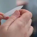 Potret seseorang sedang merawat kukunya menggunakan nail tools.