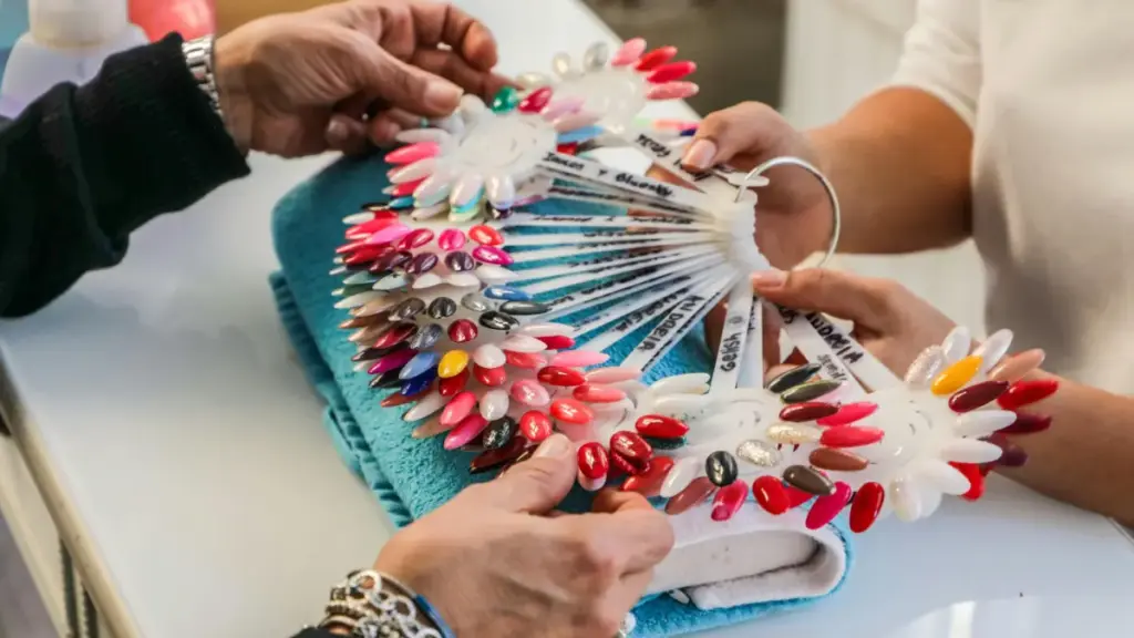 Potret sederet contoh warna kutek yang ditunjukkan nail technician kepada pelanggannya