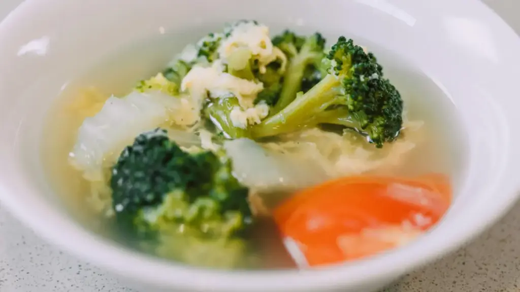 Potret semangkuk sup berisi kuah dengan potongan wortel, sawi, dan brokoli serta telur