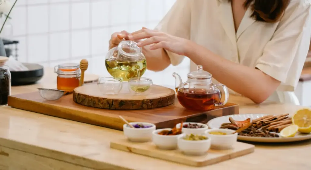 Potret seseorang sedang menuangkan teh artisan ke dalam gelas teh