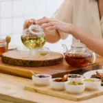 Potret seseorang sedang menuangkan teh artisan ke dalam gelas teh