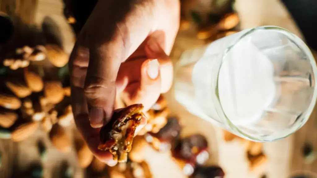 Potret kurma yang dipegang dan segelas susu disimpan berdampingan diatas nampan kayu