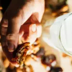 Potret kurma yang dipegang dan segelas susu disimpan berdampingan diatas nampan kayu