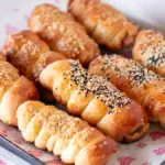 Potret sepiring puff pastry dengan isian sosis dengan topping keju dan biji wijen