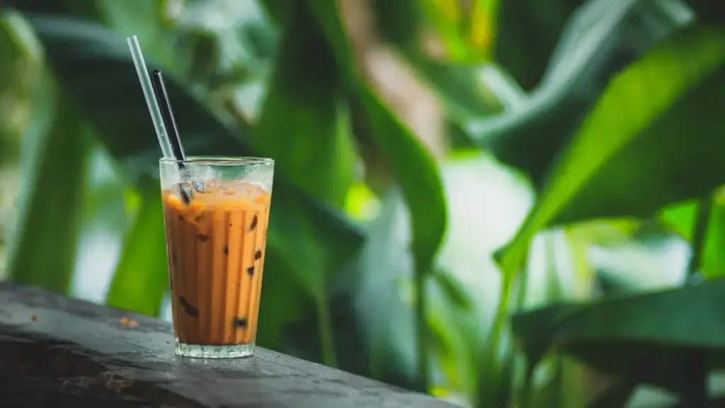 Potret segelas milk tea dengan sendok dan sedotan.