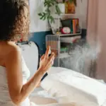 Potret seseorang sedang menyemprotkan linen spray ke bantal