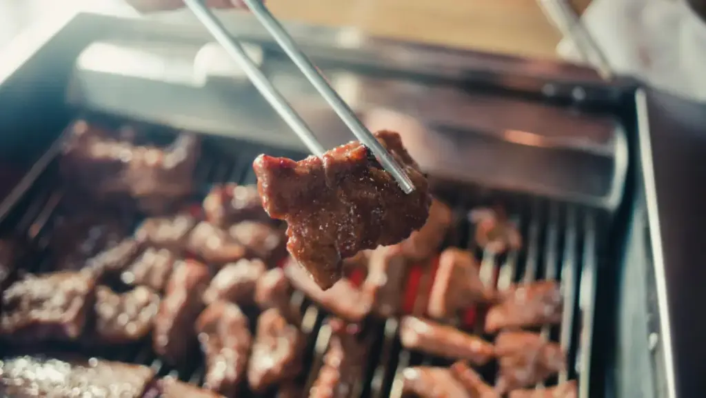 Potret sepotong dagin sapi yang dipanggang dan diambil menggunakan sumpit.