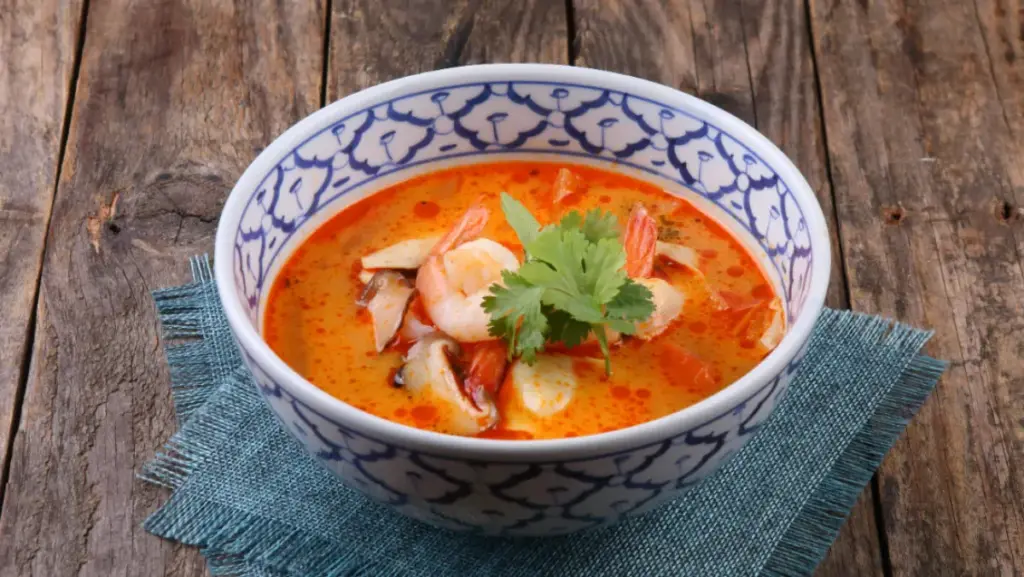 Potret semangkuk tomyum tersaji di atas kain berwarna biru