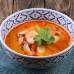 Potret semangkuk tomyum tersaji di atas kain berwarna biru