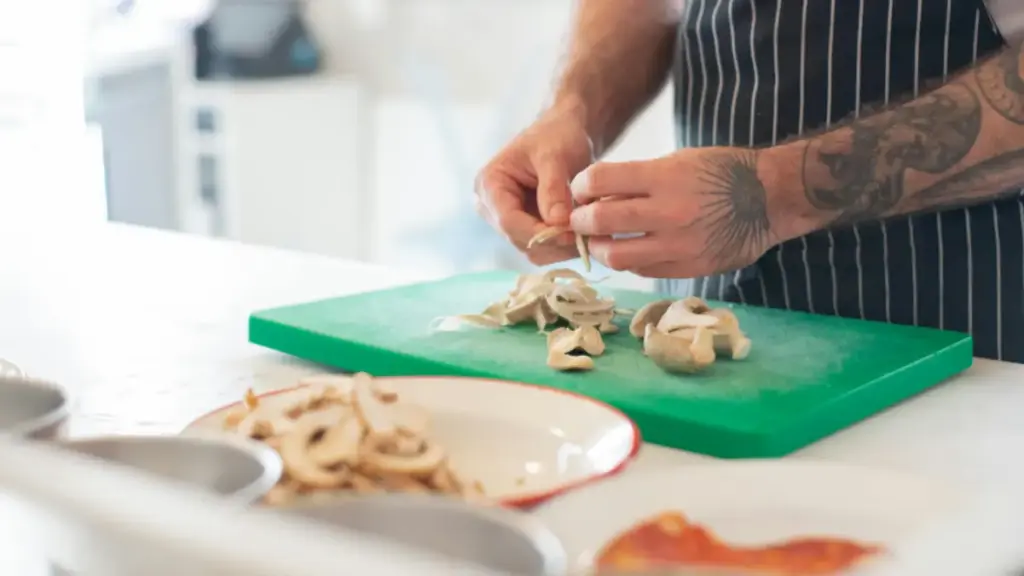 Potret seseorang sedang membersihkan jamur di atas talenan