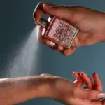 Potret seseorang sedang menyemprotkan parfum ke titik nadi