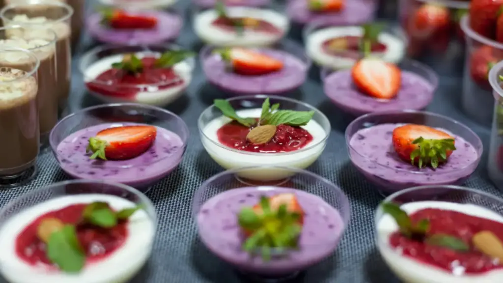 Berbagai macam panna cotta terpajang rapi dengan topping krim dan stroberi.