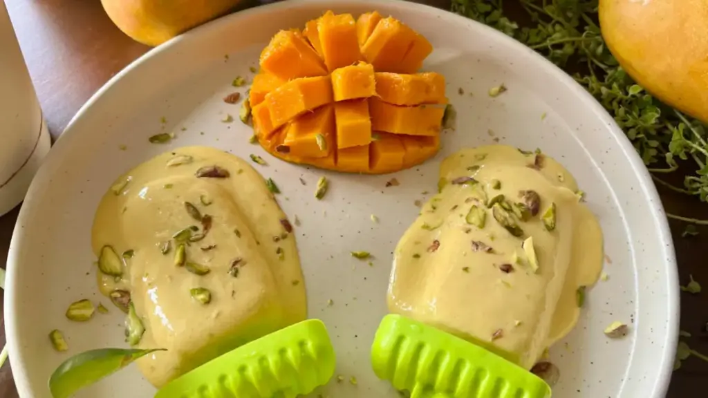 popsicle dan mangga tertata di atas piring dengan taburan kelopak bunga sebagai hiasan.