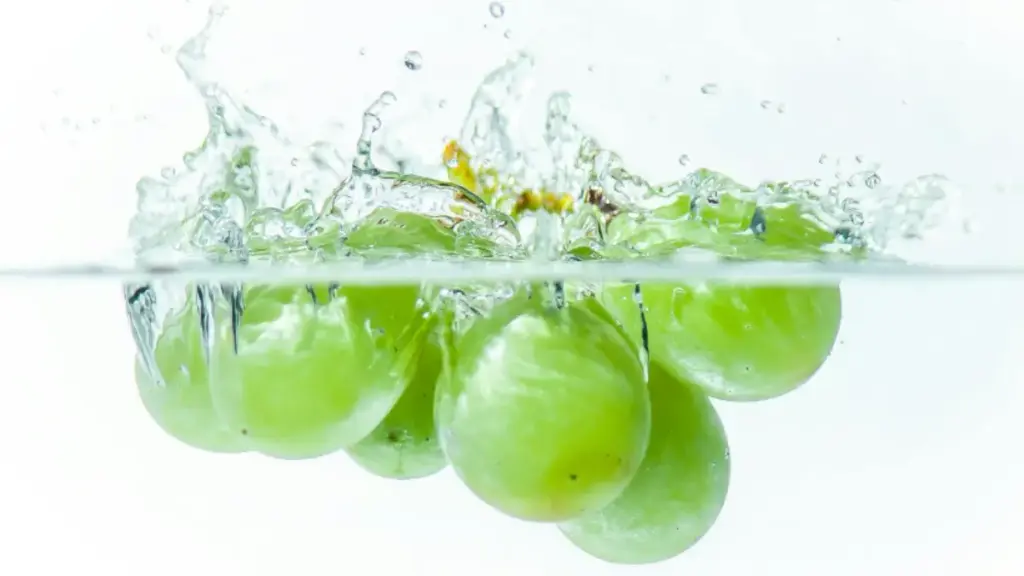 Buah anggur shine muscat yang dijatuhkan hingga mengeluarkan percikan air.