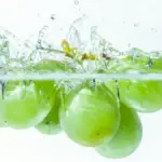 Buah anggur shine muscat yang dijatuhkan hingga mengeluarkan percikan air.