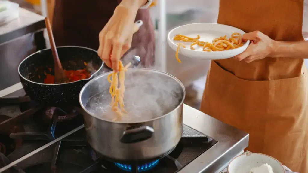 Potret sesorang memasak pasta di atas panci dan saus secara bersamaan