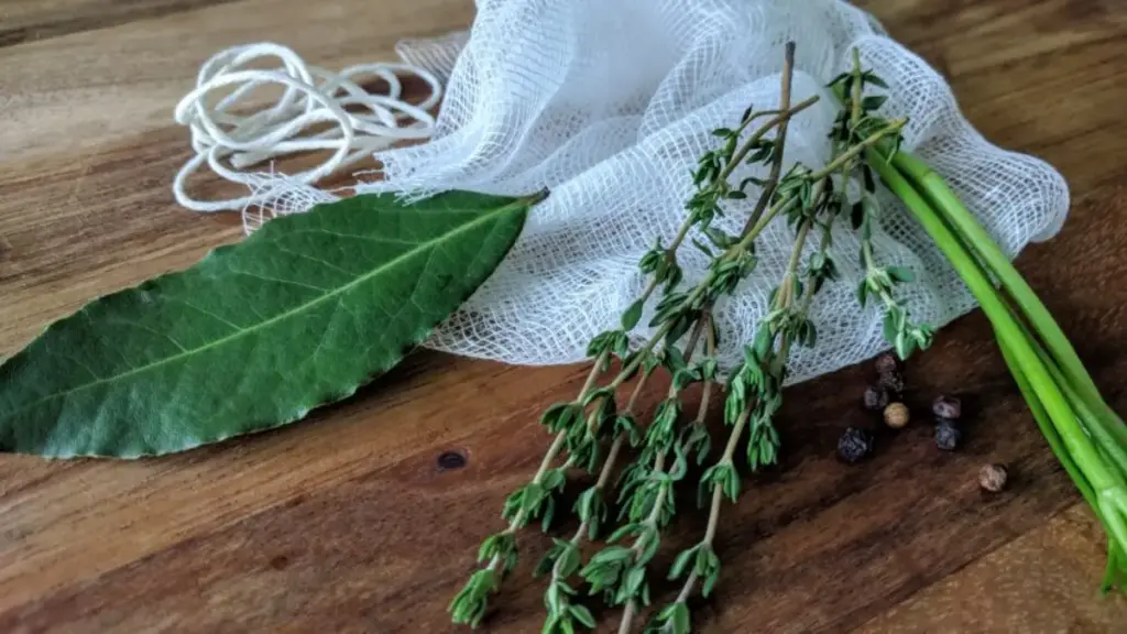 Potret bay leaf, rosemary, celery, dan black pepper tergeletak di atas meja dengan kain ikat serta tali kasur