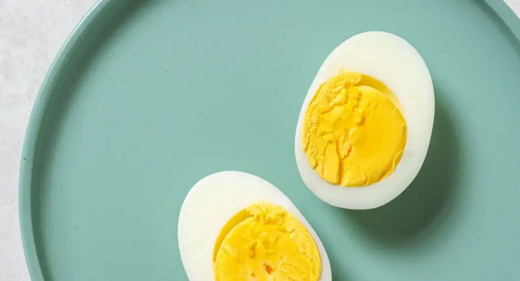 telur rebus yang dibelah dua menampilkan kuning telur yang sempurna di atas piring sarapan sehat, menggambarka