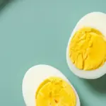 telur rebus yang dibelah dua menampilkan kuning telur yang sempurna di atas piring sarapan sehat, menggambarka