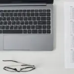 gambar berisi laptop, selembar kertas ujian dan pensil