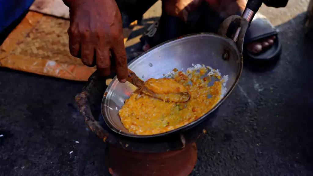 Potret seseorang sedang membuat kerak telor menggunakan tungku.