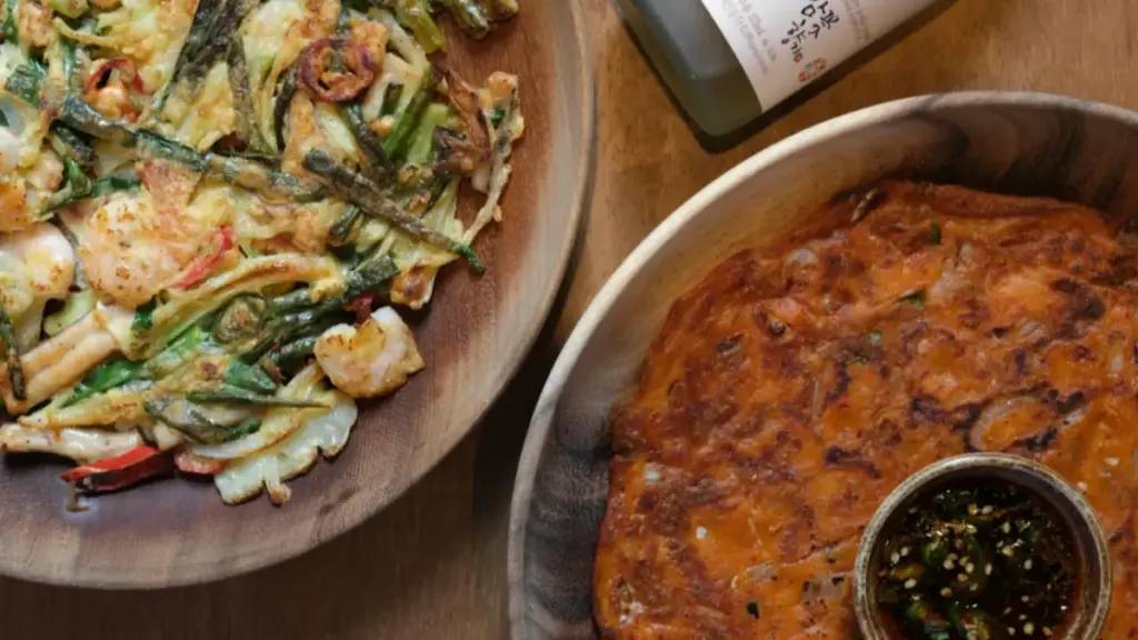 Potret pajeon seafood dan pajeon kimchi ditata bersebelahan dengan sebotol soju.