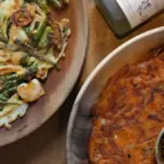 Potret pajeon seafood dan pajeon kimchi ditata bersebelahan dengan sebotol soju.