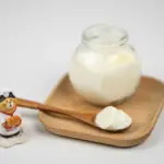 Potret segelas yogurt dengan sendok kayu dan miniatur kucing