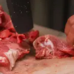 Ilustrasi seseorang sedang memotong daging diatas talenan menggunakan pisau