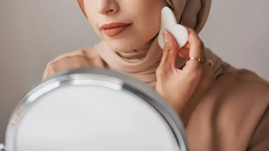 Potret perempuan berhijab sedang menggunakan gua sha