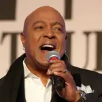 Potret peabo bryson sedang bernyanyi dan memegang mic
