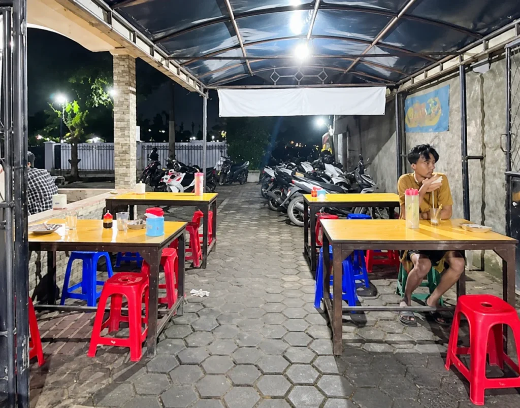 Suasana Warung Makan Motekar 5 pada malam hari dengan meja makan, kursi plastik,