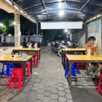 Suasana Warung Makan Motekar 5 pada malam hari dengan meja makan, kursi plastik,