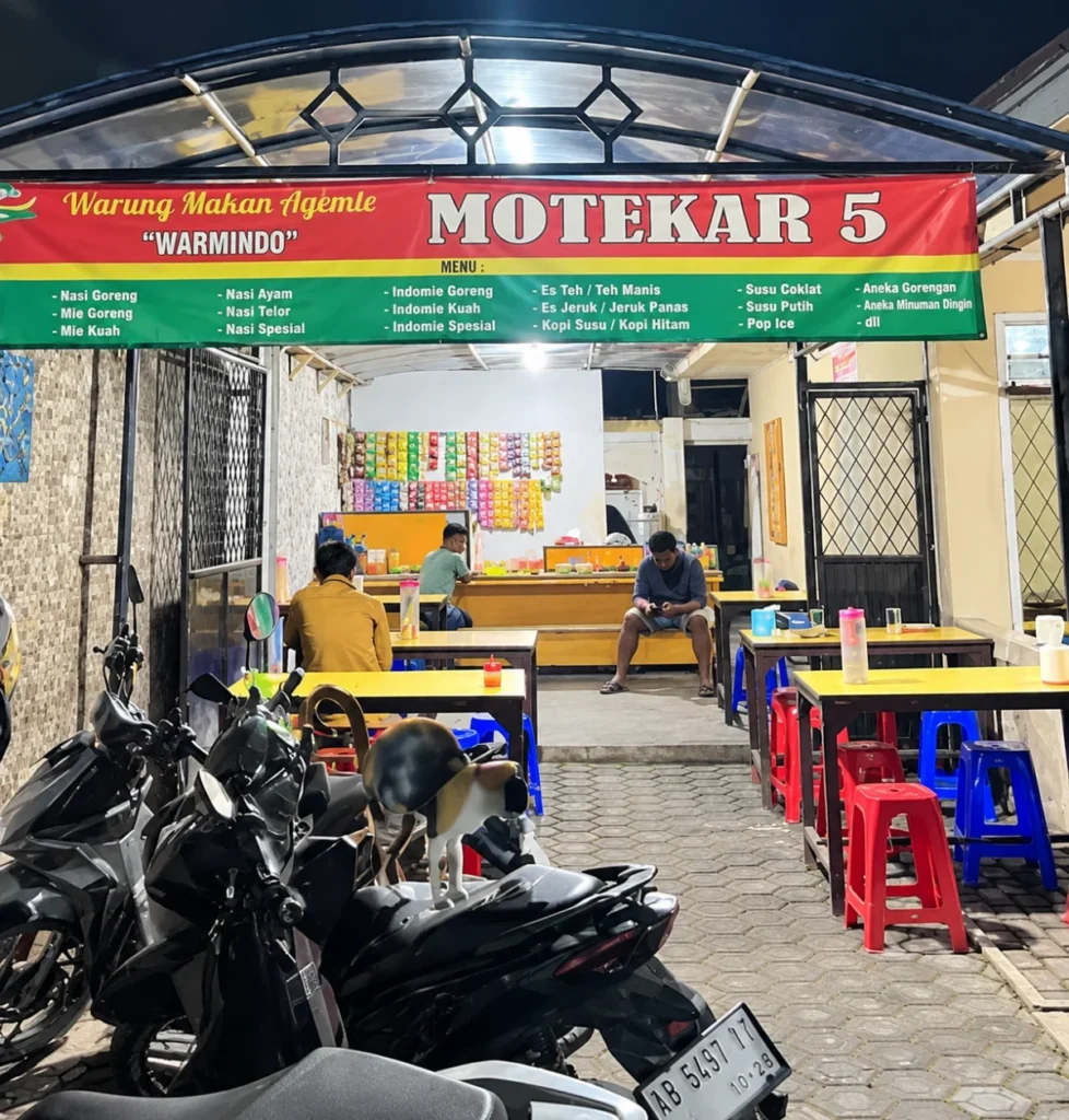 Suasana Warung Makan Motekar 5 pada malam hari dengan meja makan, kursi plastik,